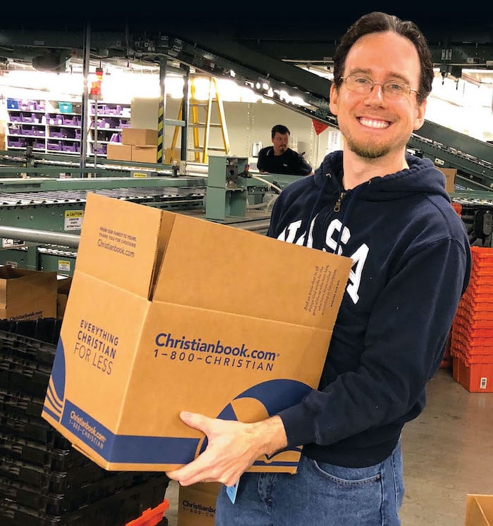 Staff member holding a Christianbook box in the warehouse